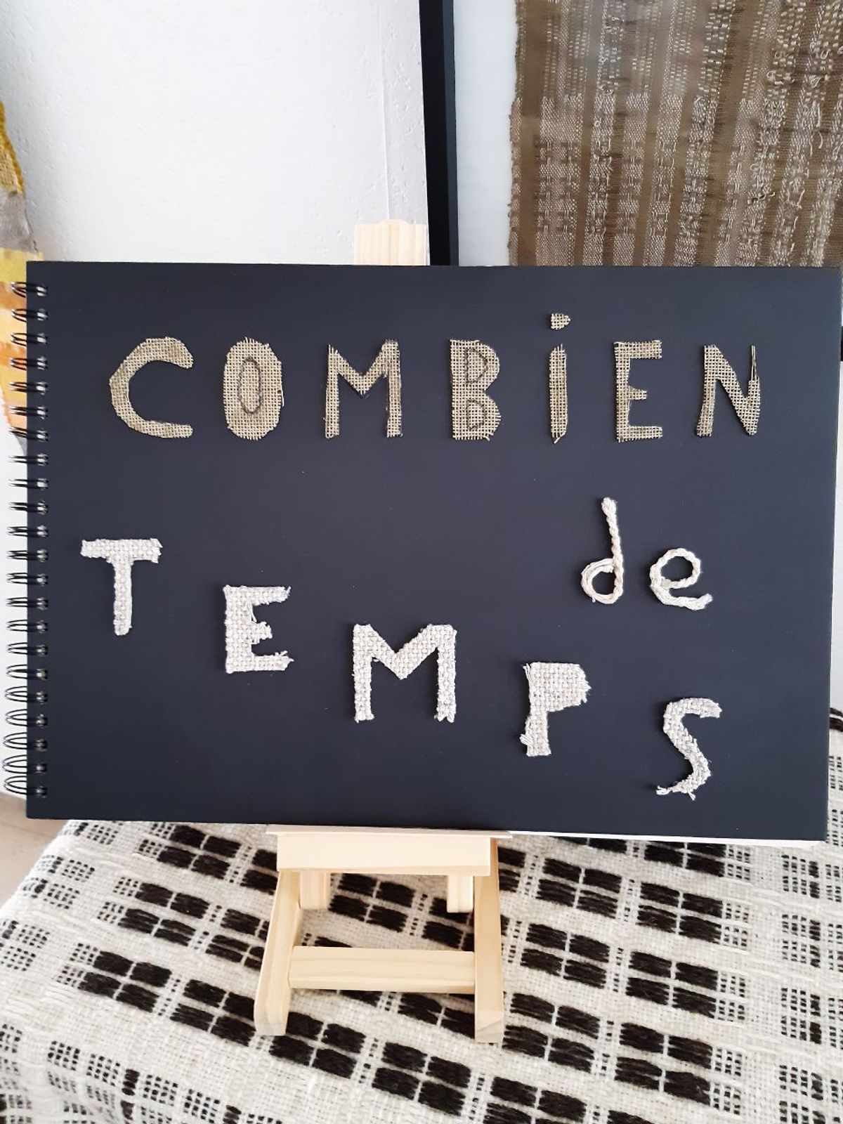 Un livret noit avec écrit 'combien de temps' de manière artistique en lettres colées